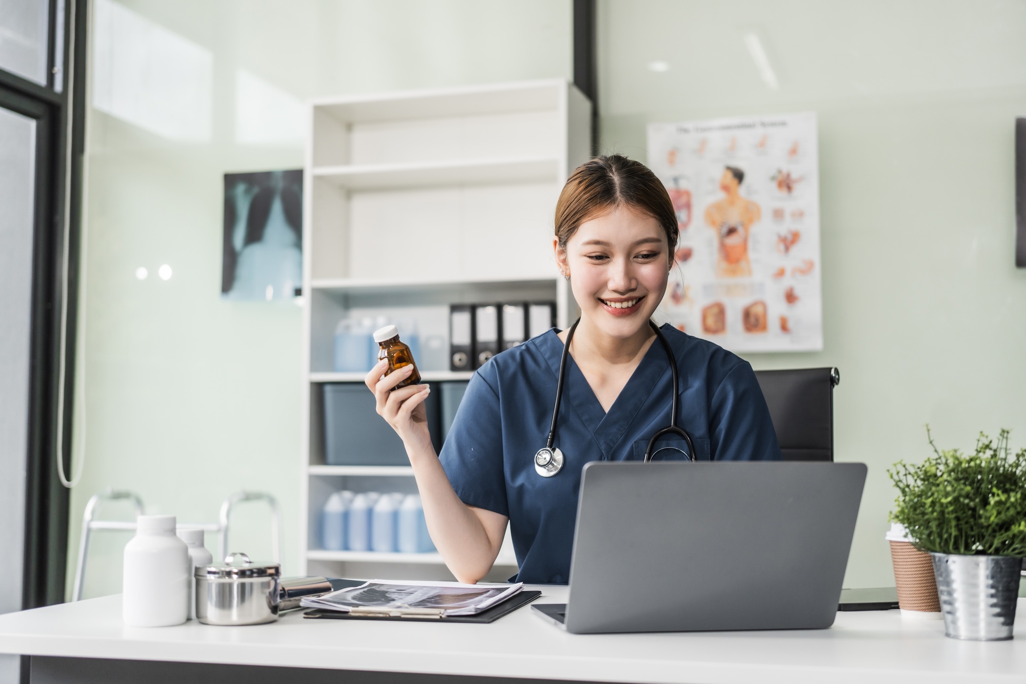 Remote Medical Office 3 A young Asian nurse providing online consultations, seated at her desk with a laptop. She offers